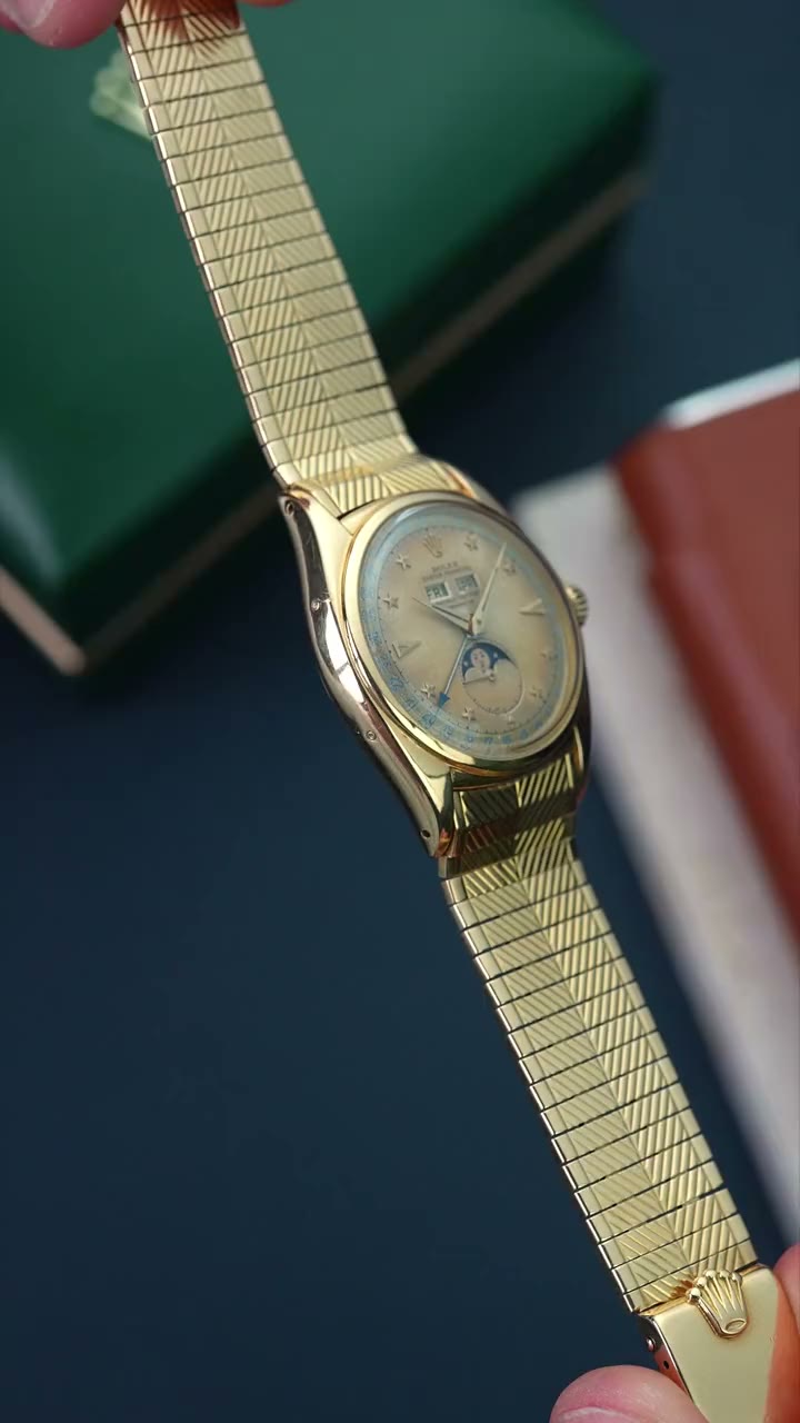 Twenty-second video showcasing the vintage gold Rolex ref. 6062 Stelline — moonphase triple calendar with star hour markers — held up between two hands against the original green Rolex presentation box, turning to reveal the engraved bracelet and dial detail