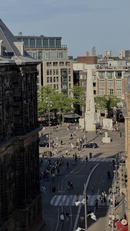 View from above over Dam Square in Amsterdam, the National Monument obelisk and the Royal Palace, people crossing the square below