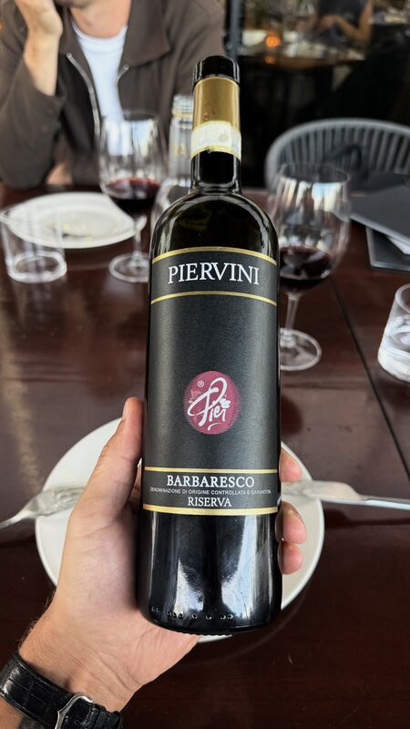 A bottle of Piervini Barbaresco Riserva held above the dinner table at Mr Porter
