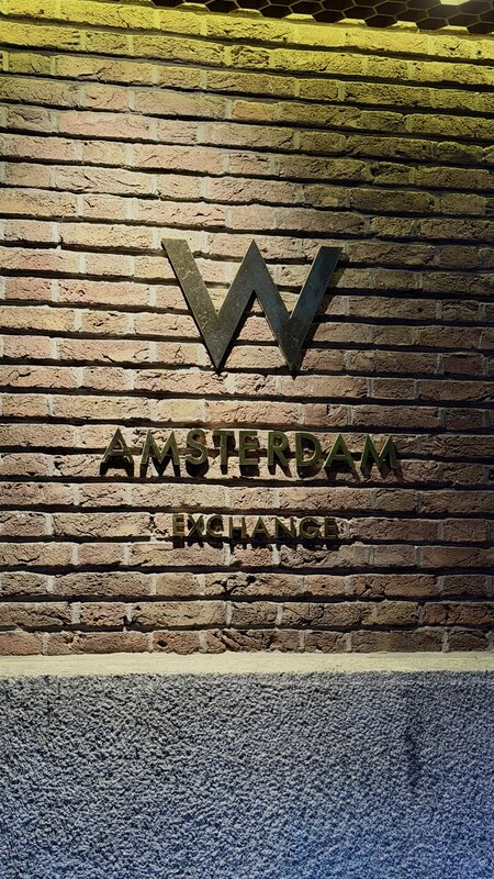 Brass W Amsterdam Exchange lettering mounted on a brick wall inside the hotel