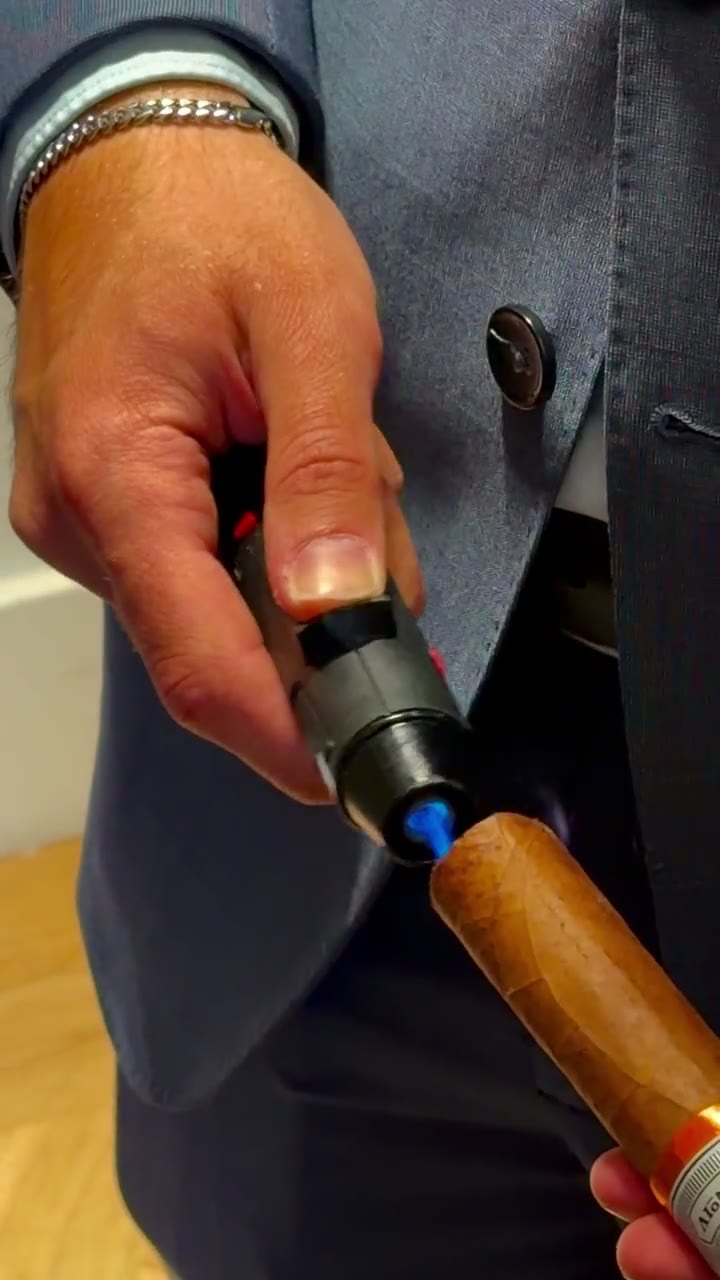 Silent close-up video of a blue torch flame lighting the end of a cigar