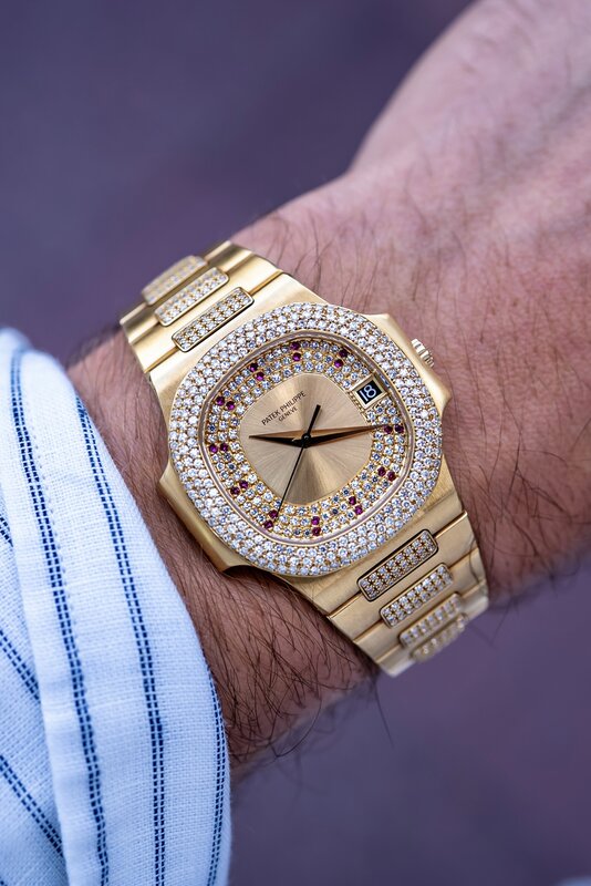 Patek Philippe Nautilus full pavé gold with rubies on wrist — striped blue and white shirt sleeve