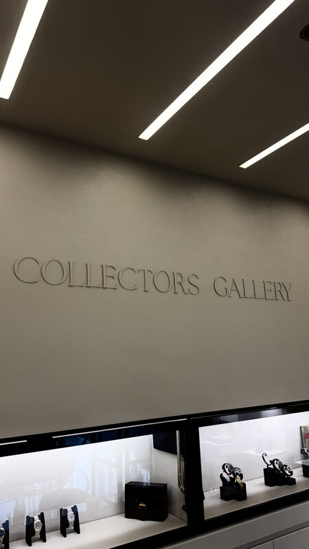 Collectors Gallery boutique wall — embossed brand signage in muted tones, display cases below