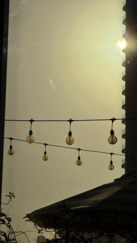 Black string lights with round bulbs strung across a clear Dubai sky at dusk