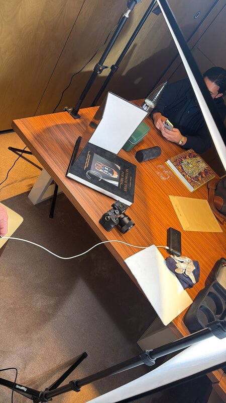 Portable photo studio set up on a wooden table — softbox lights, camera, a watch staged on white paper