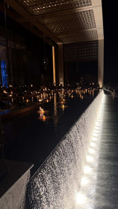 Inside Atlantis the Royal at night — ornate chandelier above a long reflecting pool