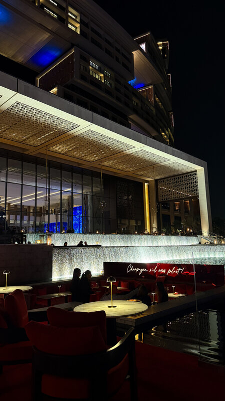 Atlantis the Royal exterior at night — neon-lit terrace, reflective pool, Dubai sky behind