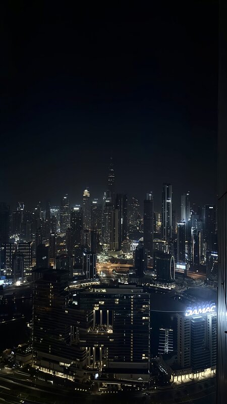 Dubai city skyline at night from a hotel window — Burj Khalifa lit up among Business Bay towers