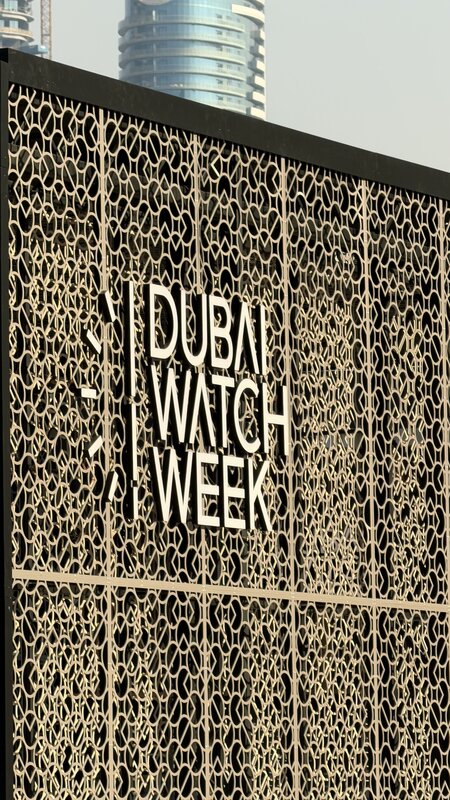 Dubai Watch Week signage cut into a golden mesh wall, Burj Khalifa visible behind