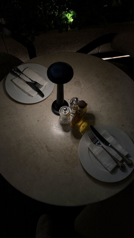 Intimate dinner table for two — marble top, linen napkins, ambient lamp
