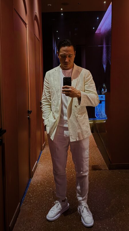 Mirror selfie of Jimmy in a cream linen suit and white sneakers — Paramount hotel hallway