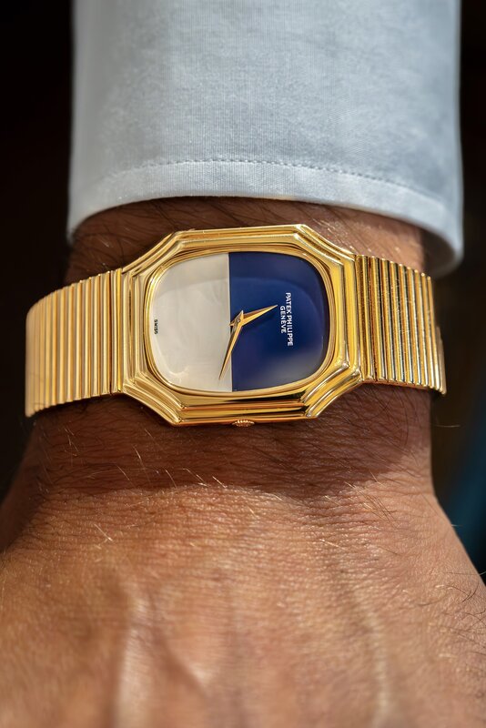A yellow-gold Patek Philippe on an integrated bracelet with a two-tone blue and white dial, worn under a pale shirt cuff