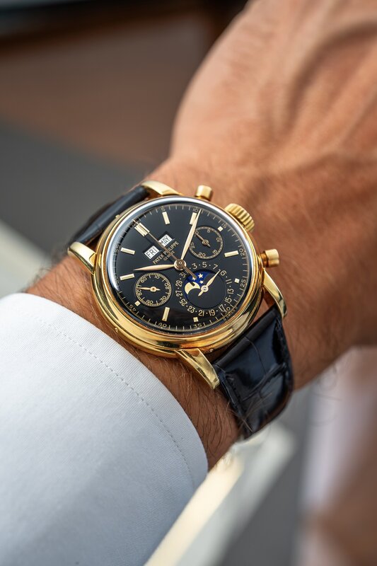 A closer view of a yellow-gold Patek Philippe 2499, showing its black dial, calendar apertures, moon phase, date scale and round chronograph pushers