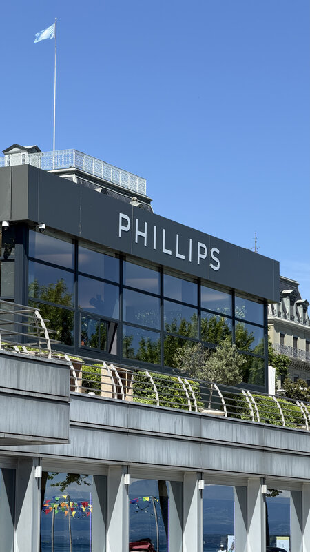 The Phillips building in Geneva, its name on the panel above the glass frontage under a clear sky
