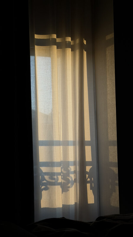 Morning light through hotel curtains and wrought-iron balcony in Geneva