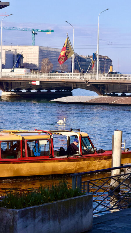 Yellow Mouette water-taxi on Lake Léman with the Pont du Mont-Blanc and a Geneva flag in the background