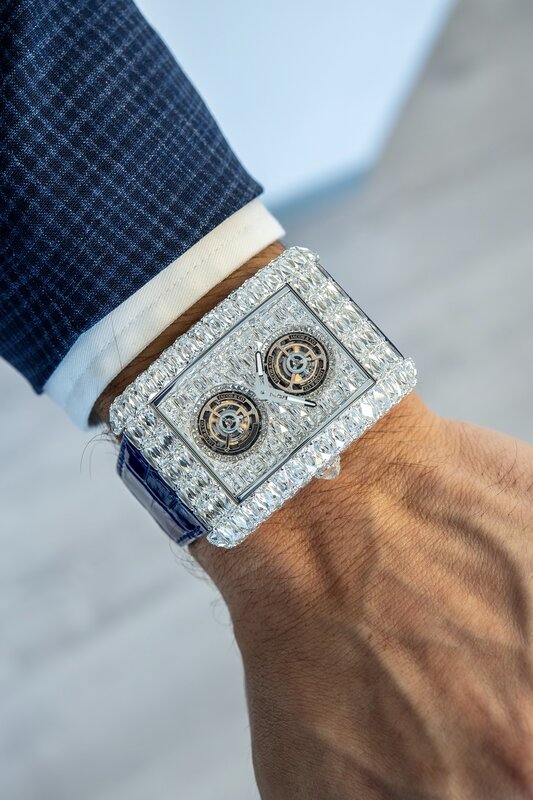 Jacob & Co Twin Tourbillon fully set with baguette diamonds on blue alligator strap on wrist, navy checked suit sleeve