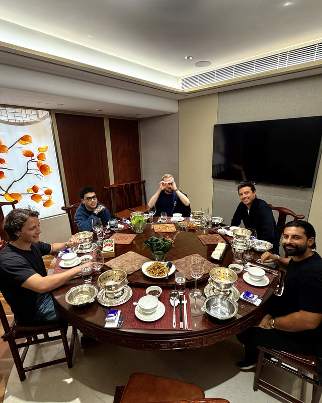 A group around a large round dining table in Hong Kong, dishes and teacups covering the lazy Susan