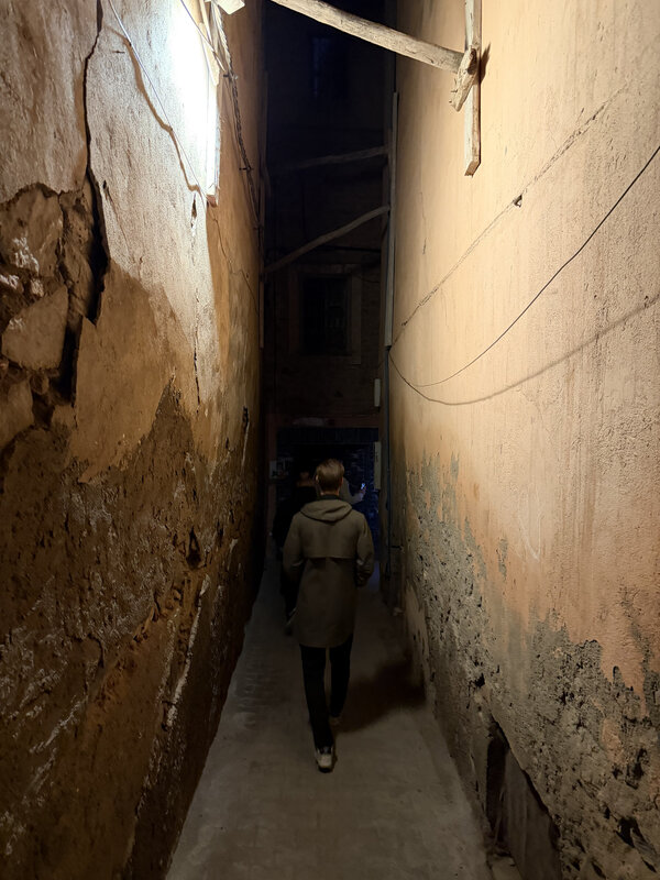Walking through a narrow Medina alleyway at night — old plaster walls