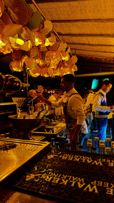 Bartender working behind the Kabana bar under copper lantern lights — white apron, low light