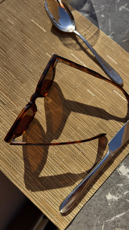 Tortoiseshell sunglasses on a golden place mat at a restaurant table