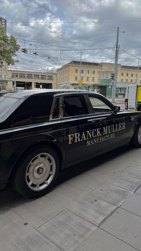 Black Rolls-Royce Phantom lettered Franck Muller Manufacture along the door, parked on a Geneva street under tram wires
