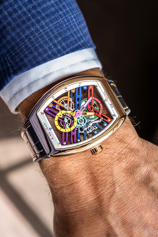 Franck Muller Vanguard skeleton on the wrist in sunlight, rose-gold case revealing rainbow-coloured movement bridges, navy alligator strap