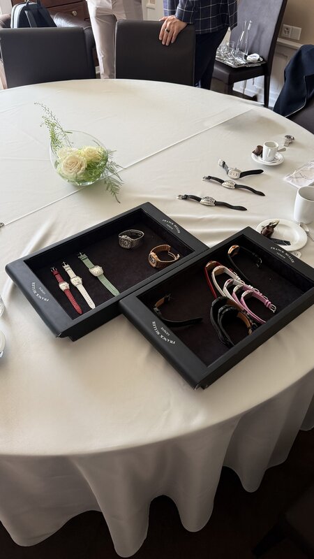 Franck Muller presentation trays of watches laid out on a white-clothed round table in the showroom, a low bowl of white roses and espresso cups alongside