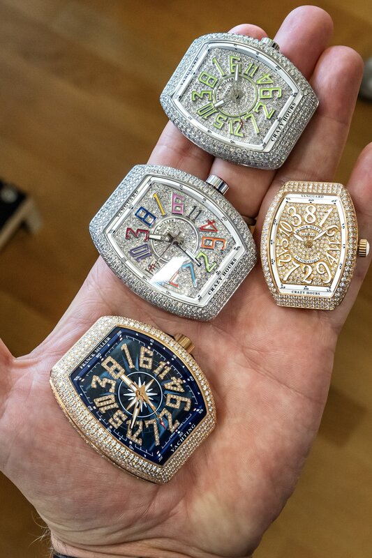 Four fully diamond-set Franck Muller watches cradled in one hand, Vanguard and Crazy Hours models in pavé cases with colour, blue and gold dials