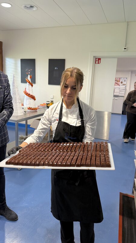 A chocolatier in apron presenting a tray of freshly made pralines during the Watchland lunch